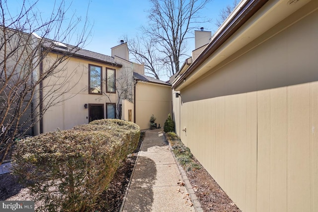 view of side of home featuring a chimney and stucco siding