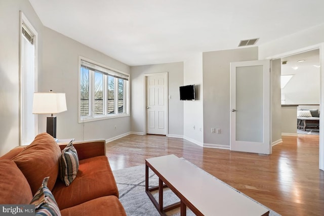 living room featuring wood finished floors, visible vents, and baseboards