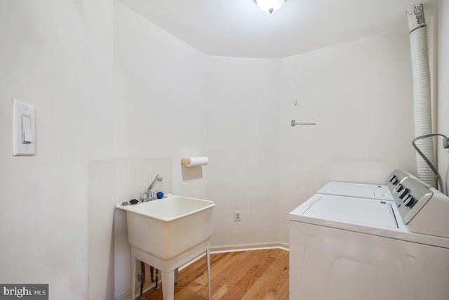 laundry area with light wood-type flooring, laundry area, independent washer and dryer, and a sink