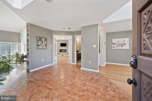 entryway with light wood finished floors, a skylight, and baseboards