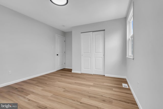 unfurnished bedroom featuring light hardwood / wood-style flooring and a closet