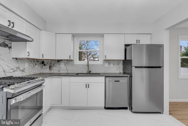 kitchen with decorative backsplash, appliances with stainless steel finishes, light wood-type flooring, sink, and white cabinets