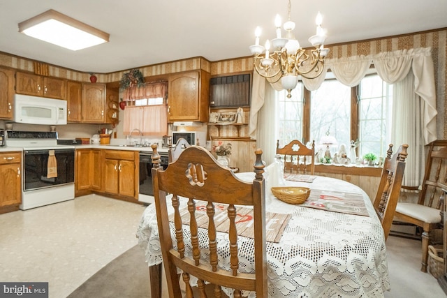 kitchen featuring wooden walls, sink, a chandelier, and white appliances