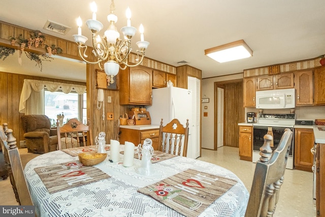 dining room with wood walls and a chandelier