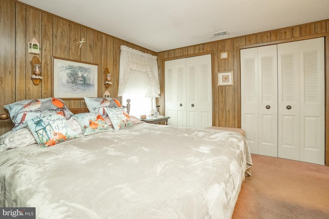 carpeted bedroom with two closets and wood walls