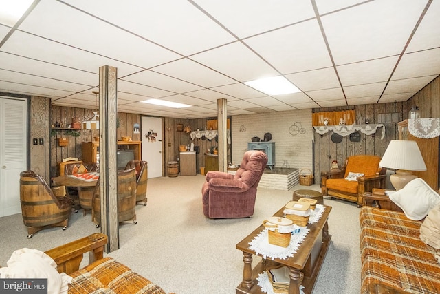 living room featuring carpet flooring, a paneled ceiling, and wood walls