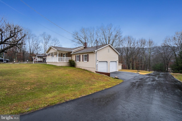 view of side of home with a lawn, a garage, and covered porch