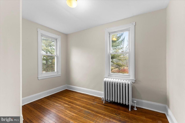 unfurnished room featuring radiator heating unit and dark hardwood / wood-style flooring