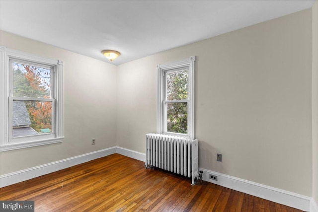 spare room featuring radiator heating unit and dark wood-type flooring