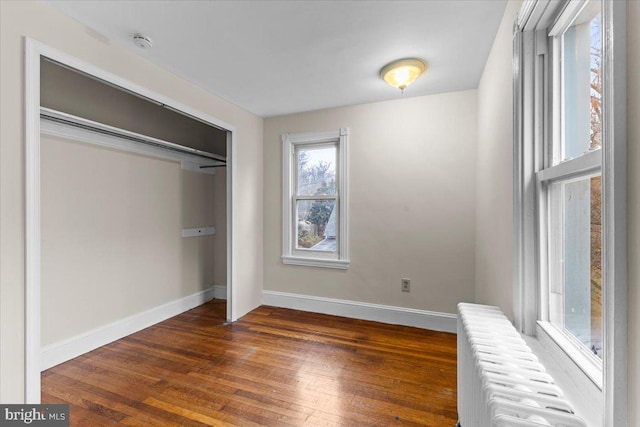 unfurnished bedroom with radiator, a closet, and dark hardwood / wood-style floors