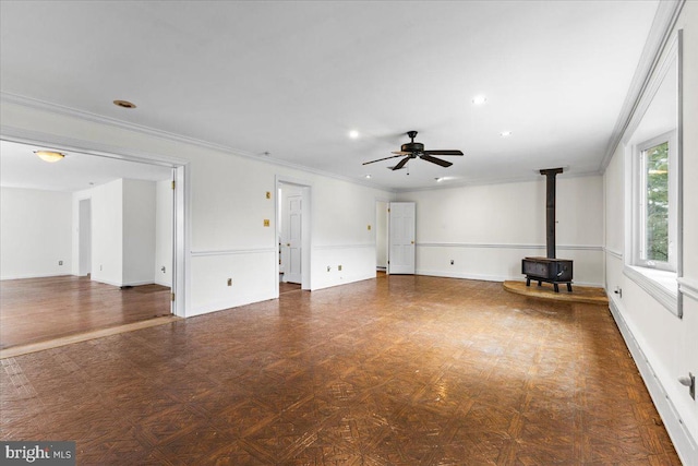 unfurnished living room with a wood stove, ceiling fan, and ornamental molding