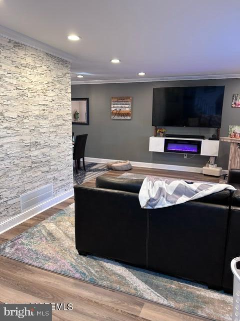 living room featuring wood-type flooring and crown molding