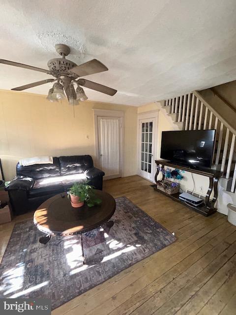 living room with ceiling fan, dark wood-type flooring, and a textured ceiling