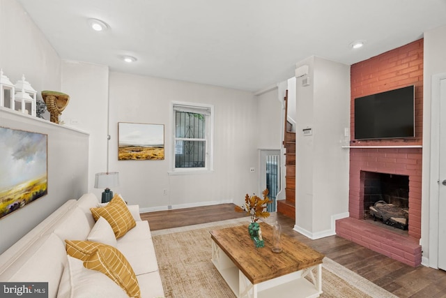 living room with a brick fireplace and hardwood / wood-style flooring