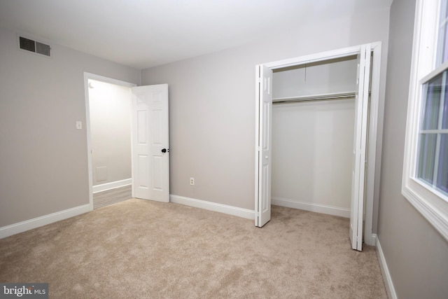 unfurnished bedroom with light carpet and a closet