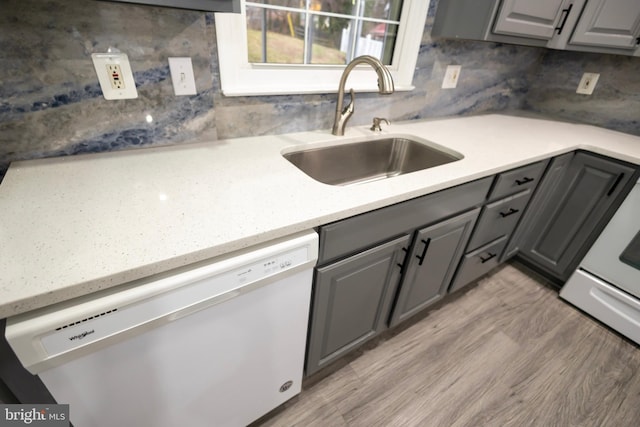 kitchen with dishwasher, sink, light hardwood / wood-style floors, gray cabinets, and decorative backsplash