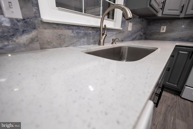 kitchen with gray cabinetry, sink, tasteful backsplash, light stone counters, and dark hardwood / wood-style floors