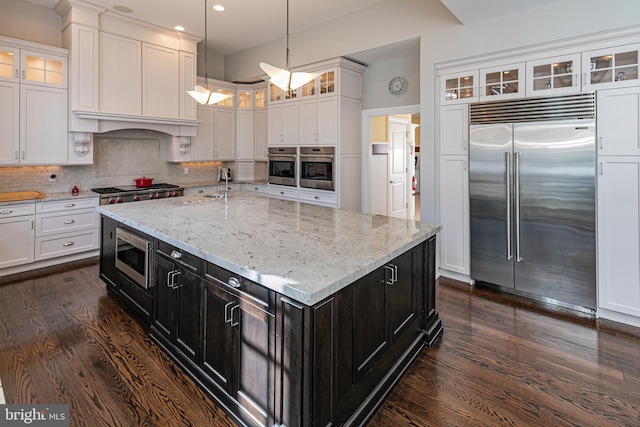 kitchen with white cabinetry, dark wood finished floors, decorative backsplash, and built in appliances