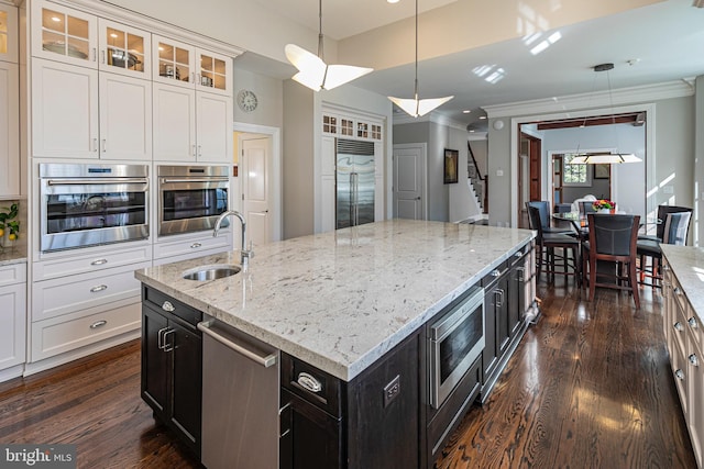 kitchen featuring glass insert cabinets, dark wood finished floors, a sink, and built in appliances