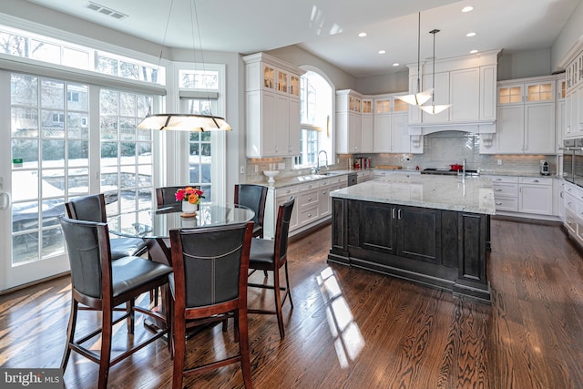 kitchen with backsplash, dark wood finished floors, visible vents, and a center island