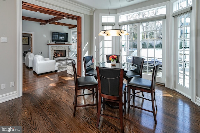 dining space with visible vents, dark wood finished floors, a lit fireplace, and baseboards