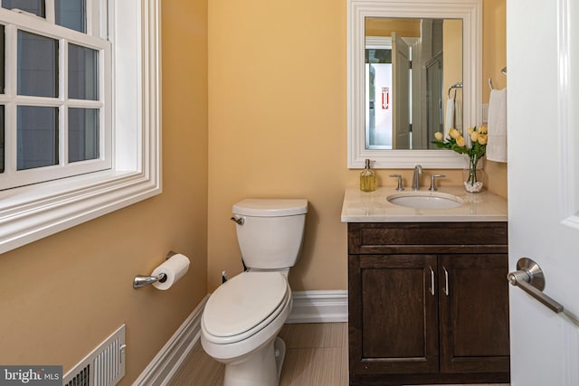 bathroom with toilet, baseboards, visible vents, and vanity