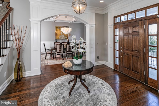 entryway with dark wood-type flooring, arched walkways, a decorative wall, and an inviting chandelier