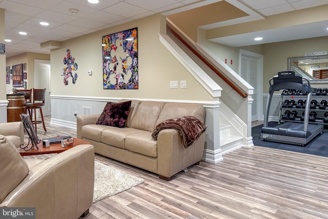 living area with a paneled ceiling, visible vents, stairway, and wood finished floors