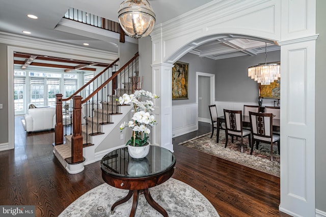 entrance foyer with dark wood-style floors, arched walkways, an inviting chandelier, coffered ceiling, and stairs