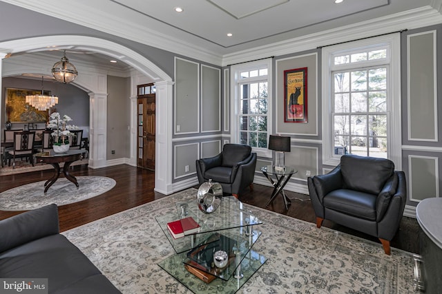 living room with arched walkways, decorative columns, and a decorative wall