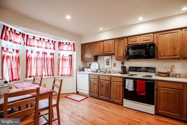 kitchen with white appliances, light hardwood / wood-style floors, and sink