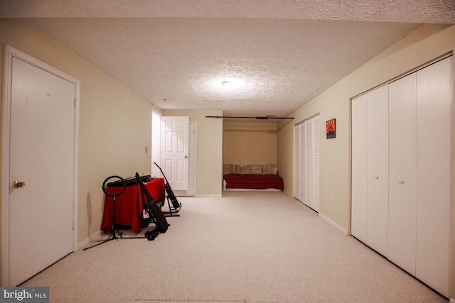 hallway featuring a textured ceiling and light carpet