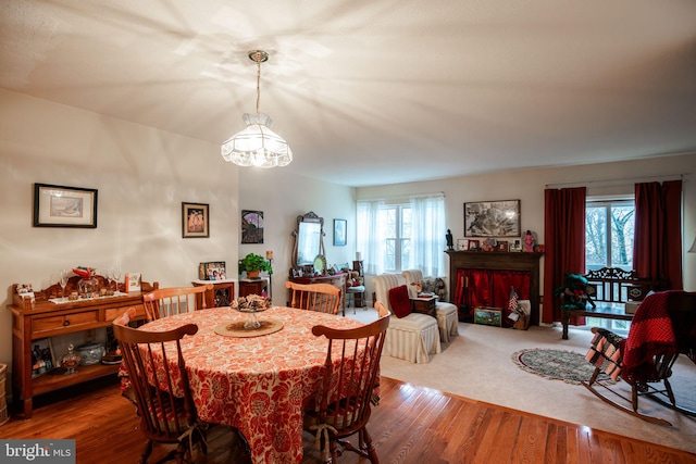 dining area featuring a healthy amount of sunlight, a notable chandelier, and hardwood / wood-style flooring