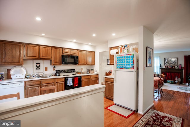 kitchen with light hardwood / wood-style flooring, white appliances, and sink