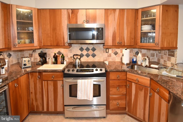 kitchen featuring tasteful backsplash, sink, light tile patterned floors, and stainless steel appliances