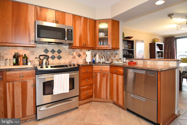 kitchen featuring backsplash, crown molding, dark stone countertops, light tile patterned floors, and stainless steel appliances