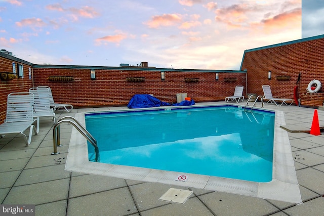 pool at dusk featuring a patio