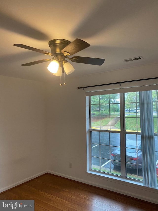 empty room with ceiling fan, hardwood / wood-style flooring, and a healthy amount of sunlight