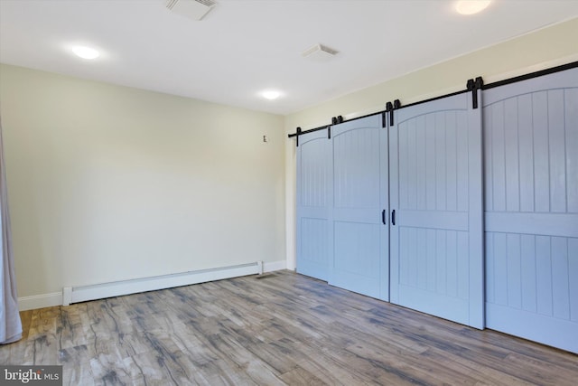 unfurnished bedroom featuring wood-type flooring, a closet, and a baseboard heating unit