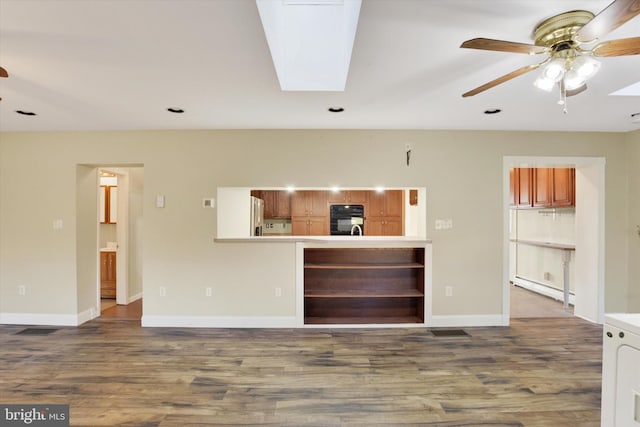 unfurnished living room with ceiling fan, wood-type flooring, washer / clothes dryer, and a skylight