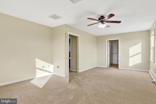 unfurnished bedroom featuring light carpet, a walk in closet, a closet, and ceiling fan