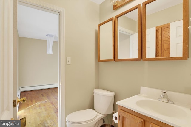 bathroom with baseboard heating, hardwood / wood-style floors, vanity, and toilet