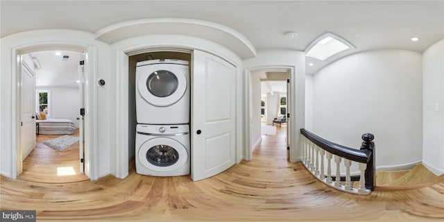 washroom with light hardwood / wood-style flooring and stacked washer and clothes dryer