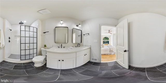 bathroom with tiled shower, vanity, toilet, and ceiling fan