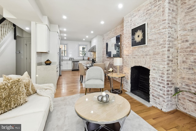 living room with light hardwood / wood-style floors and a brick fireplace