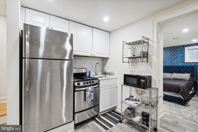 kitchen with white cabinets, light wood-type flooring, stainless steel appliances, and sink