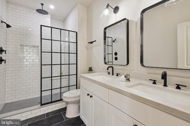 bathroom with toilet, tile patterned flooring, vanity, and tiled shower