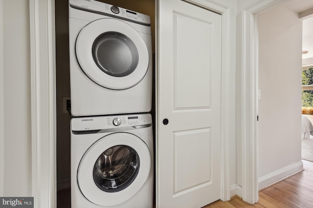 clothes washing area featuring light hardwood / wood-style flooring and stacked washer and clothes dryer