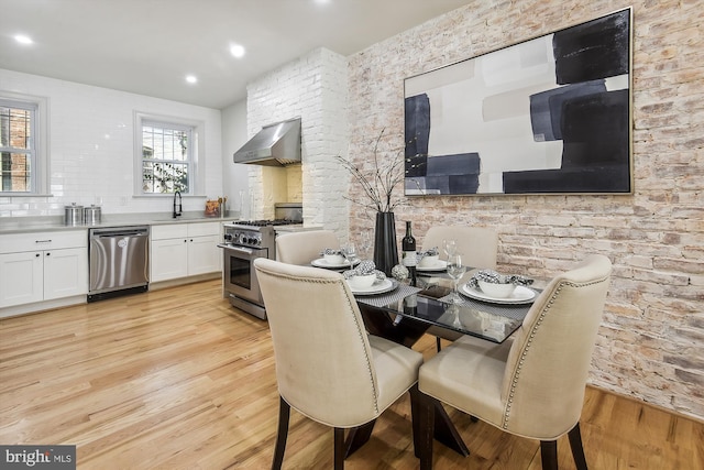 dining space with light wood-type flooring and sink