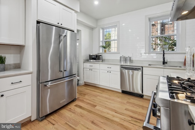 kitchen featuring sink, light wood-type flooring, stainless steel appliances, and a wealth of natural light